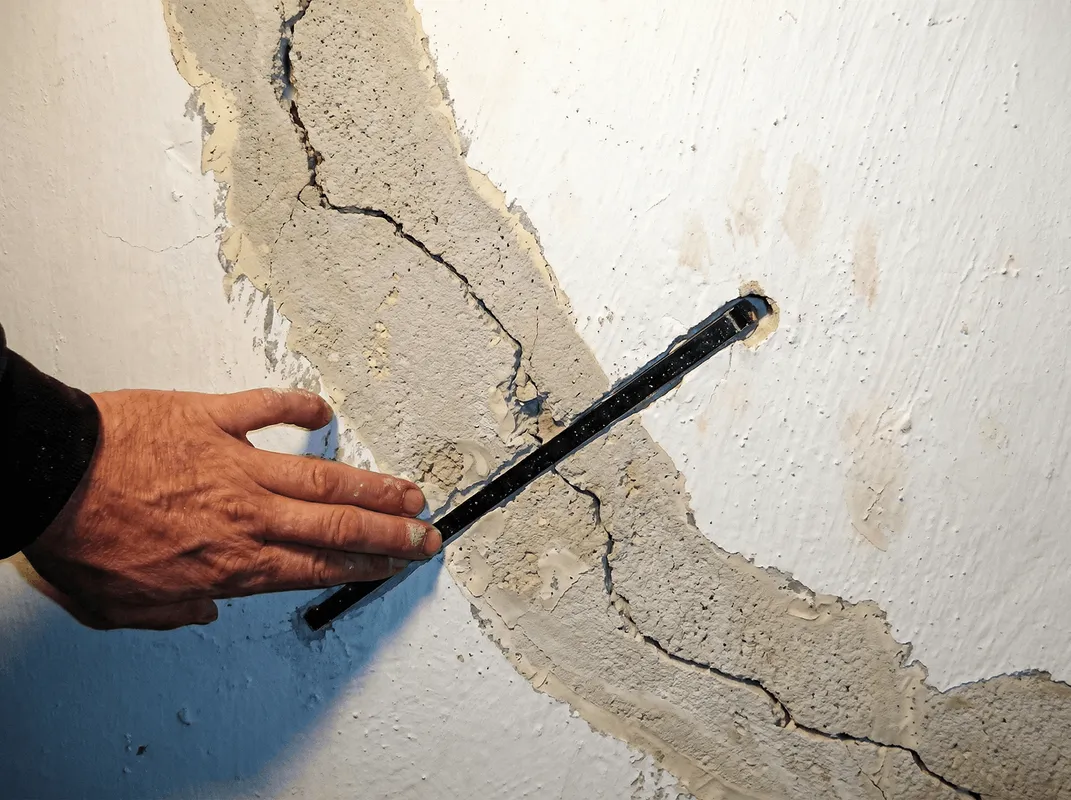 A wall with a large crack is being inspected by a professional in Reno, NV